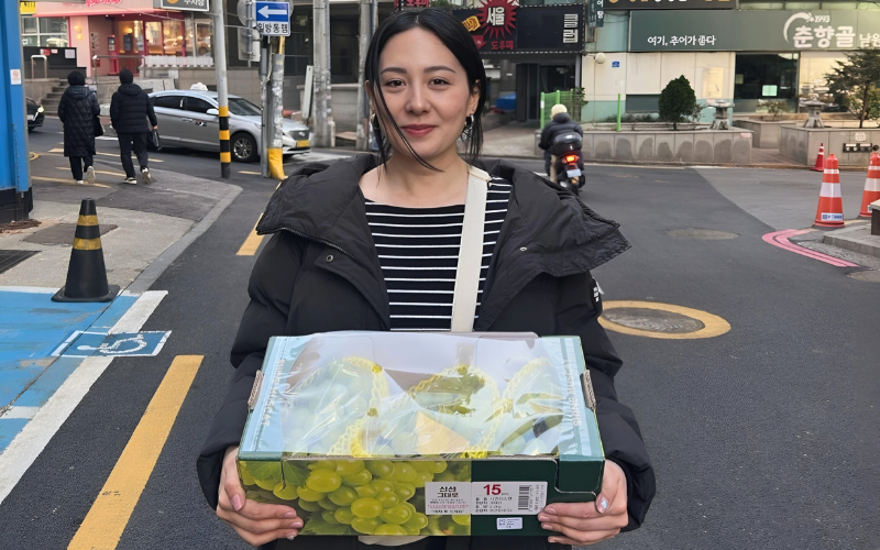 Maria celebrating Lunar New Year in Korea, carrying a box of grapes as a gift for her relatives (by Maria Athanasopoulou)